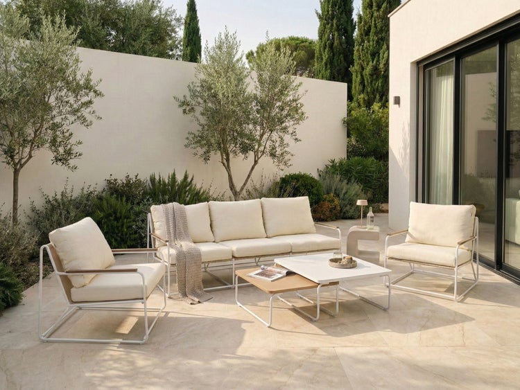 Gartenszene mit Loungemöbeln, bestehend aus Sofa, Sesseln und Tischen auf einer Terrasse.