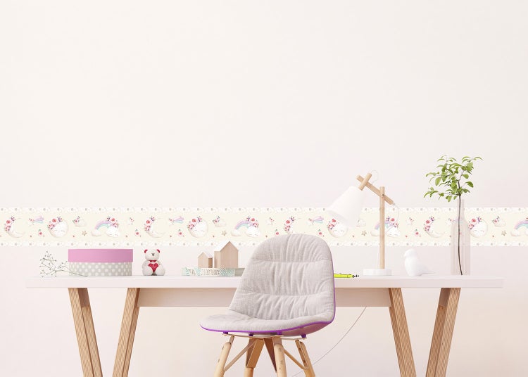 Tapetenbordüre für das Kinderzimmer mit Motiven von Mond, Regenbogen und Blumen an einer Wand über einem Schreibtisch mit Stuhl.