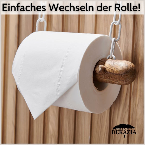 Hängender Toilettenpapierhalter aus Holz mit weißen Metallketten vor einer Holzlamellenwand. Einfacher Rollenwechsel. Dekazia Logo.