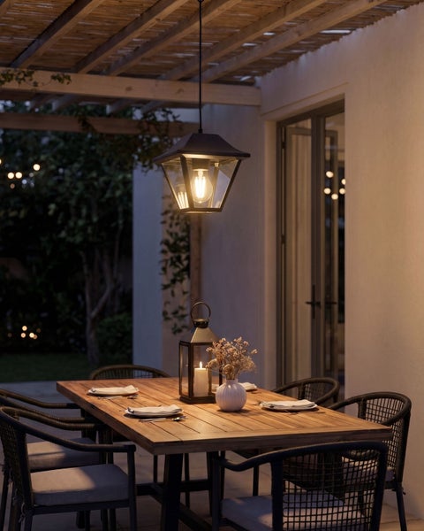 Moderne Outdoor Pendelleuchte über einem gedeckten Holztisch auf einer überdachten Terrasse bei Abenddämmerung.
