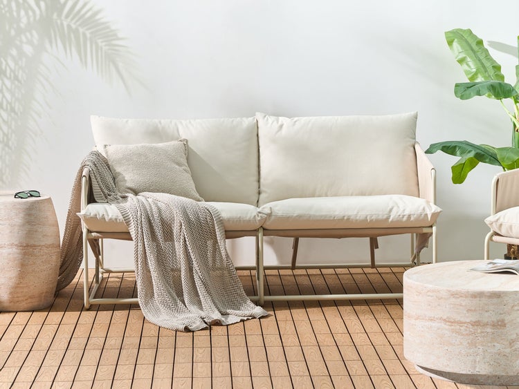 Szene mit einem Outdoor Sofa, einem Beistelltisch, einem Hocker und einer Zimmerpflanze auf einer Holzterrasse