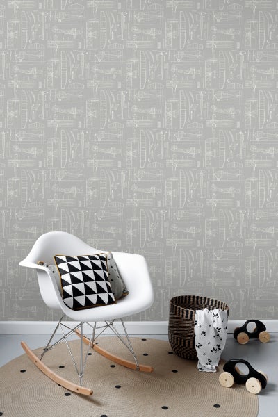 Raumansicht mit Flugzeugtapete, Schaukelstuhl, Kissen, Teppich, Spielzeugautos und Korb