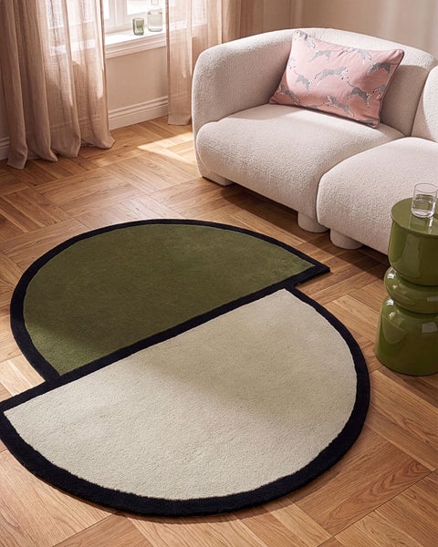Runder Wohnzimmerteppich mit geometrischem Design in einem modernen, hellen Wohnzimmer mit Parkettboden und Sofa.