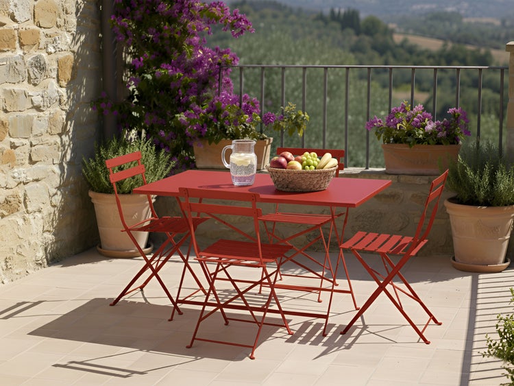 Terrassenszene mit Gartentisch, Stühlen, Obst und Pflanzen in Töpfen