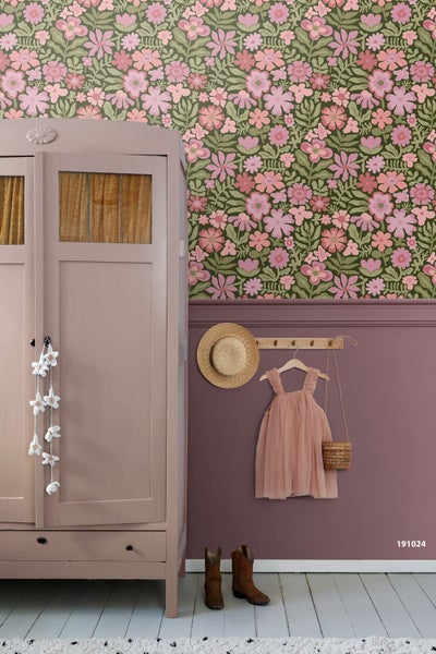 Vliestapete mit floralem Muster in Pink und Grün in einem hellen Kinderzimmer mit einem weißen Hausbett aus Holz.