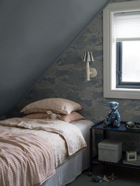 Nahaufnahme eines Rhododendronstrauchs mit hellen Blüten und blau blühenden Pflanzen