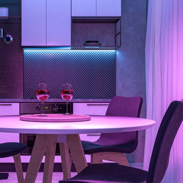 Esszimmer mit Esstisch und Stühlen in modernem Design und mit Küchenzeile im Hintergrund