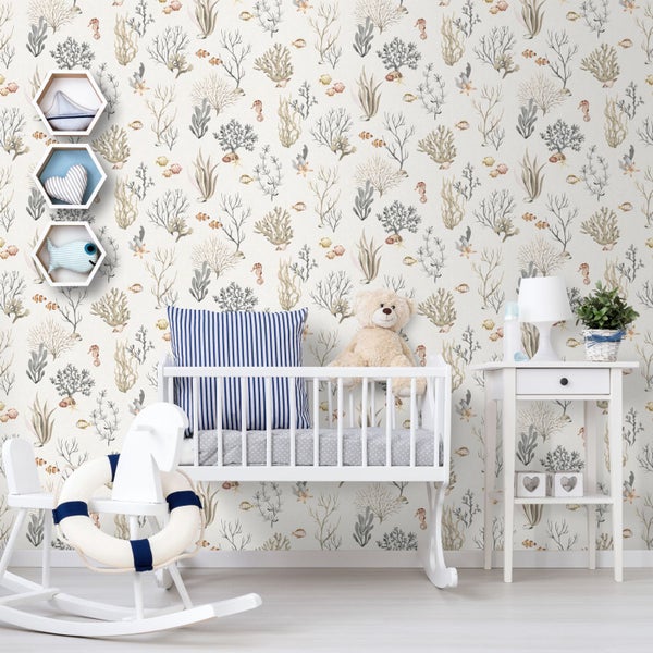 Vliestapete mit Unterwasser-Motiven in einem hellen Babyzimmer mit weißem Gitterbett, Schaukelpferd und Beistelltisch.