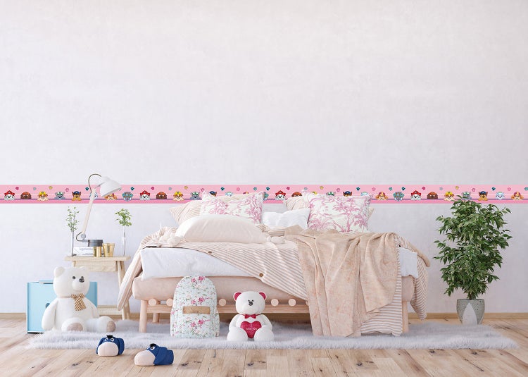 Hell eingerichtetes Kinderzimmer mit einem Holzbett, gemusterter Bettwäsche, weißem Teppich und einer Wandbordüre mit Paw Patrol Motiven.