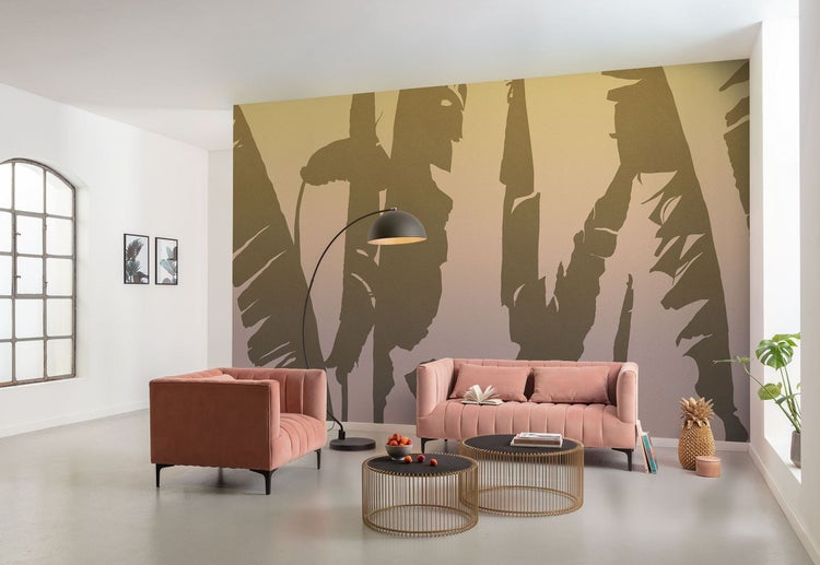 Wohnzimmer mit rosa Sofa, Sessel, Couchtischen, Stehlampe und bedruckter Tapete