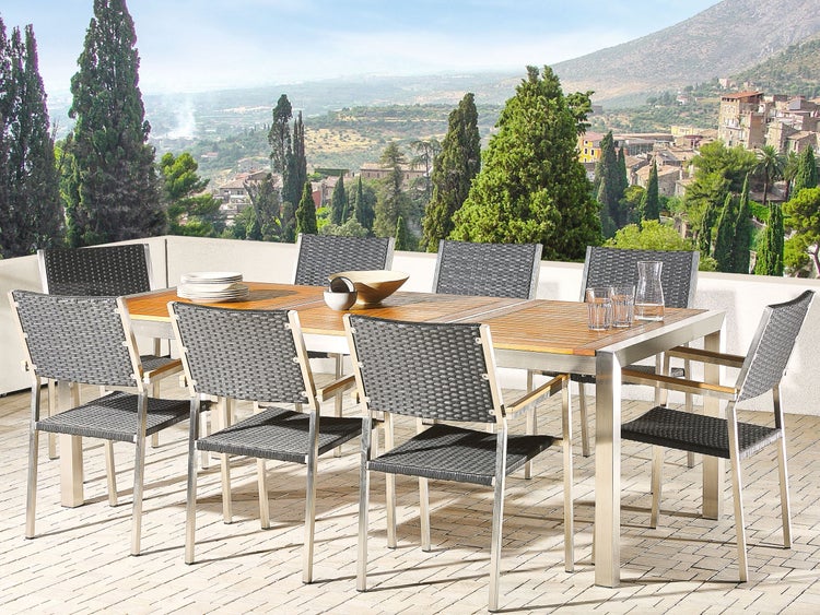 Szene mit Gartentisch aus Holz und Metall mit Flechtstühlen im Außenbereich