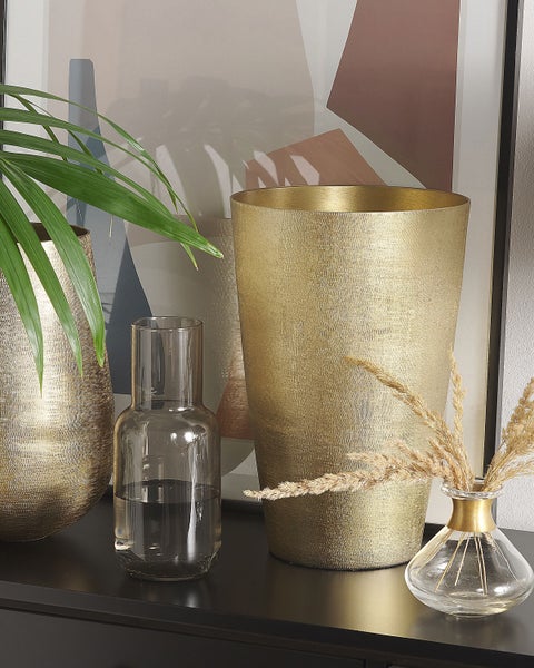 Dekorative Anordnung mit goldenen Vasen, einer Glasvase und einem abstrakten Kunstwerk für ein stilvolles Ambiente