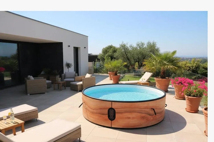 Runder Whirlpool in Holzoptik auf einer modernen Terrasse mit Gartenmöbeln, Liegen und Topfpflanzen.