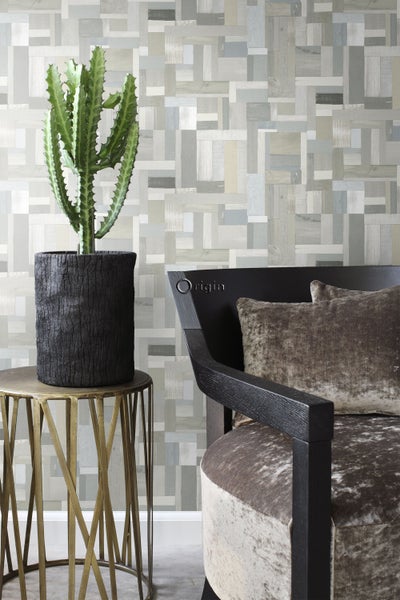 Dekoratives Interieur mit Kaktus im Topf auf Beistelltisch und Stuhl vor einer gemusterten Wand