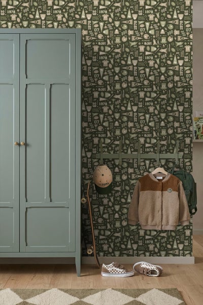 Kinderzimmer mit grüner Tapete im Sport-Design, einem grünen Schrank, einer Garderobenleiste mit Jacke und Rucksack sowie einem Skateboard.