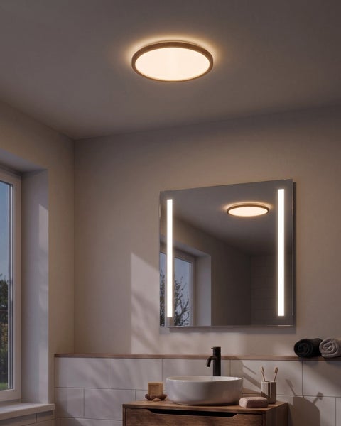 Badezimmer mit beleuchtetem Wandspiegel, Aufsatzwaschbecken und einer runden Deckenleuchte in einem modernen und funktionalen Einrichtungsstil.