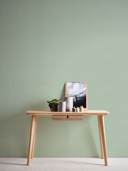 Stillleben mit Eukalyptus in einem Krug, Kerze und Dekoration auf einem Tablett vor einer Wand