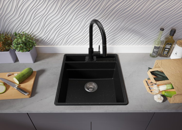 Schwarze Küchenspüle mit Abtropffläche und schwarzer Armatur auf einer Küchentheke mit Lebensmitteln