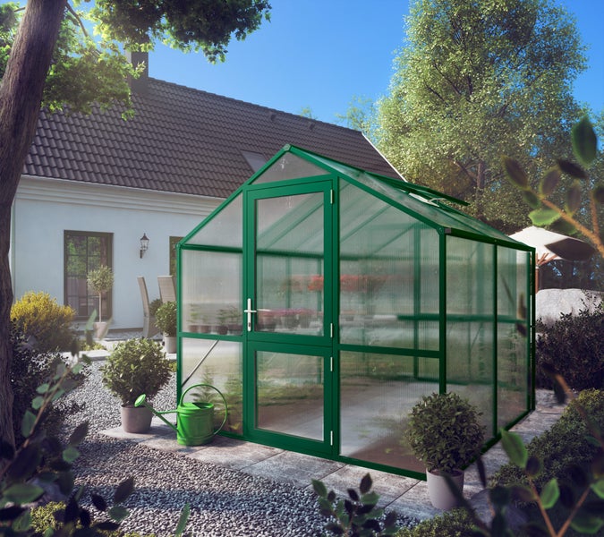 Gewächshaus mit grünem Aluminiumrahmen und Hohlkammerplatten aus Polycarbonat im Garten mit Drehtür und Dachfenster.