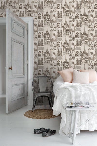 Schlafzimmer mit Bett, Beistelltisch, Stuhl und Fototapete mit Paris-Motiven