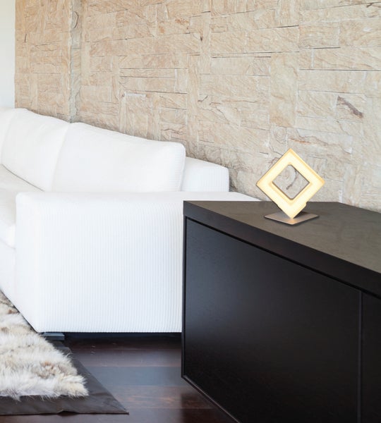 Wohnzimmer mit Sofa, Kommode und dekorativer Tischleuchte in quadratischer Form