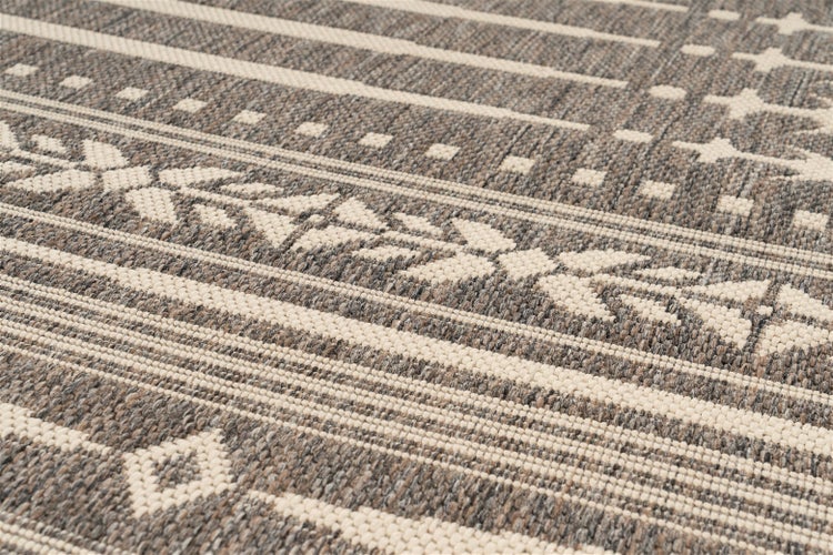 Detailansicht eines flachgewebten Teppichs mit geometrischem Muster, Streifen, Rauten und floralen Elementen.