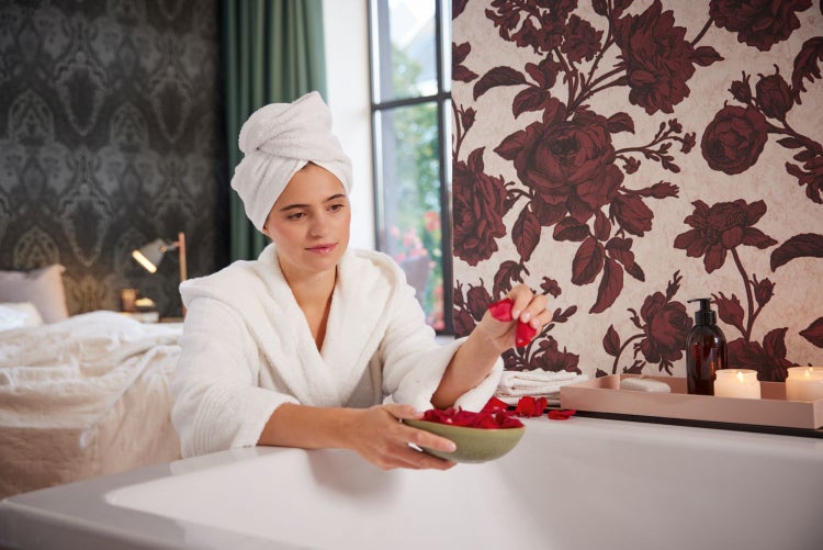 Wohnzimmer mit dunklem Ledersofa und floraler Tapete mit Rosenmuster