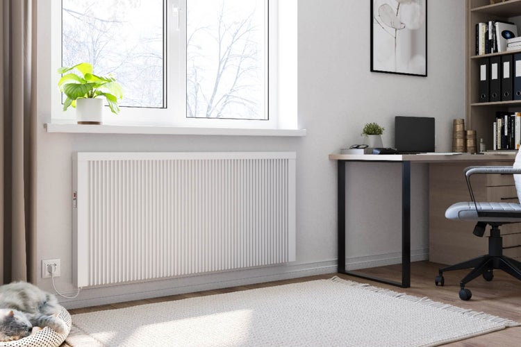 Elektrischer Flachheizkörper mit vertikaler Profilierung an einer Zimmerwand unter einem Fenster in einem modern eingerichteten Büro.