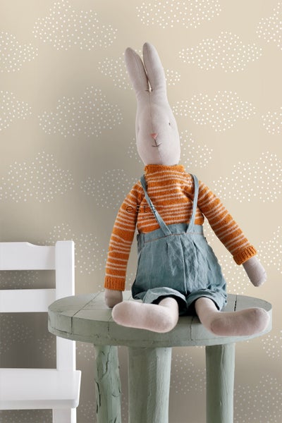 Dekoratives Stofftier-Kaninchen auf einem Beistelltisch vor einer Tapete