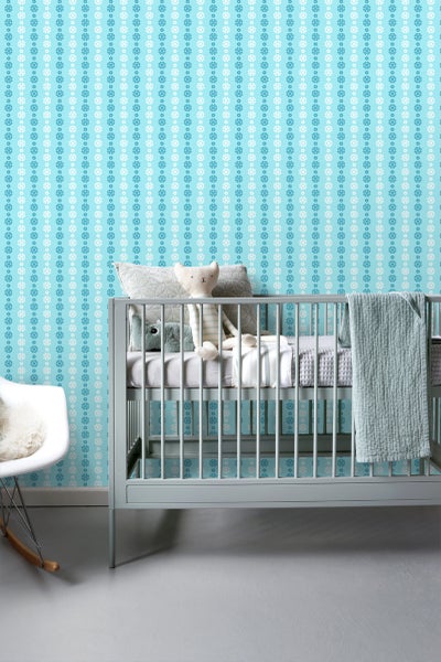 Babyzimmer mit Gitterbett und floral gemusterter Tapete