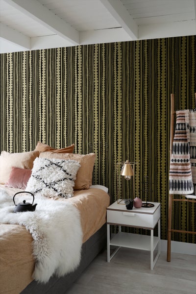 Schlafzimmer mit Bett, Nachttisch und gemusterter Tapete