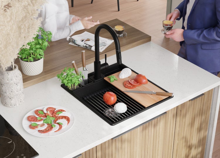Küchenspüle mit Abtropffläche, Armatur, Schneidebrett und Lebensmitteln auf einer Küchentheke.