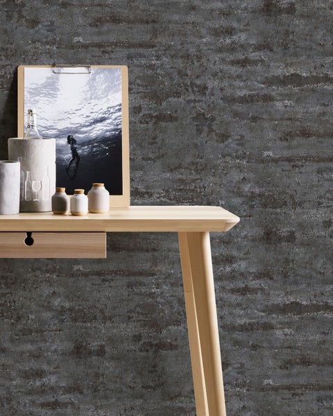 Wohnraumgestaltung mit dunkel gemusterter Tapete, einem Holztisch und dekorativen Elementen