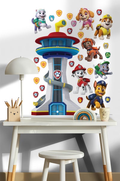 Wandaufkleber mit Motiven aus Paw Patrol neben einem Schreibtisch mit Lampe, Stiften und einem Regenbogen.