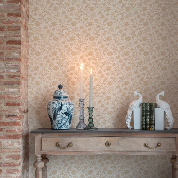 Wand mit floraler Mustertapete hinter einer hölzernen Konsole mit dekorativen Kerzenständern und Keramikvase.