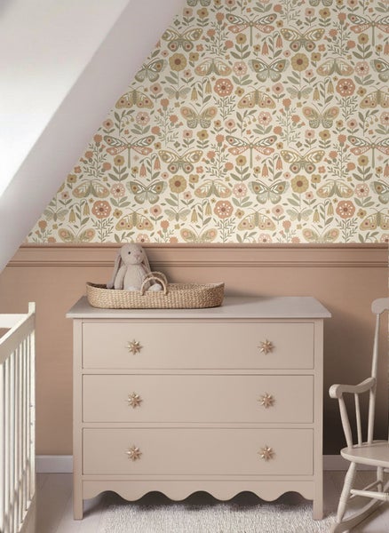 Einrichtungsidee für ein Kinderzimmer mit einer Kommode, einer Kinderwiege und einer Wand mit Blumentapete.