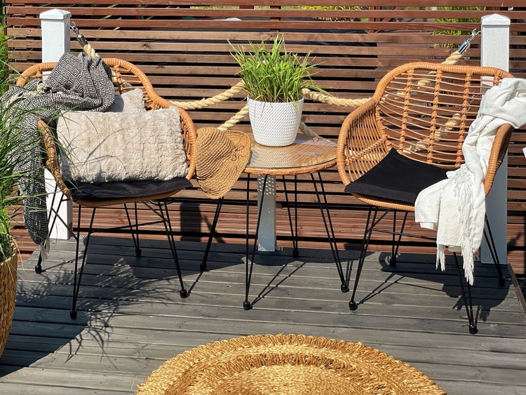Terrasse mit zwei Rattansesseln, Beistelltisch mit Glasplatte und dekorativen Accessoires