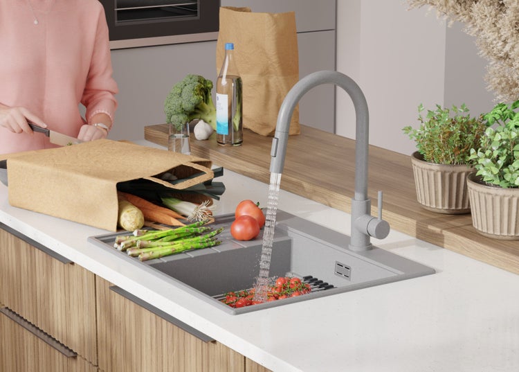 Spüle mit Wasserhahn, Gemüse und einer Person in einer modernen Küche