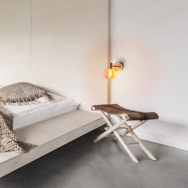 Schlafzimmer mit Bett, Wandleuchte und Hocker
