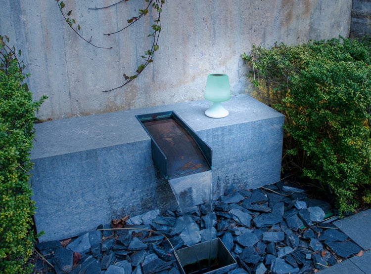 Dekorative Gartenszene mit Wasserfall, Zierkies und einer Tischleuchte