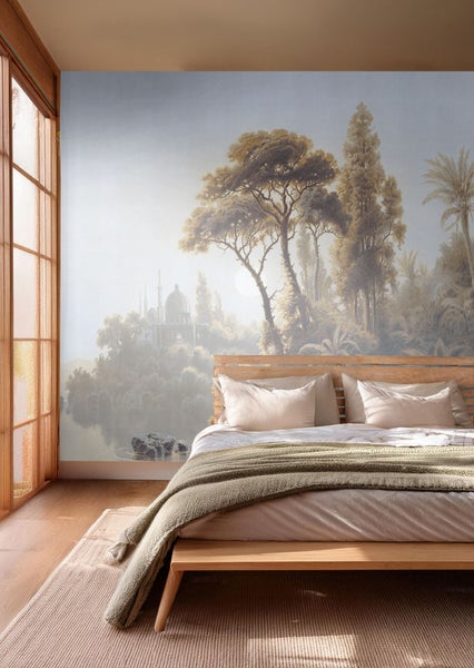 Blick auf ein Schlafzimmer mit einer Fototapete mit Baum- und Seenmotiv.
