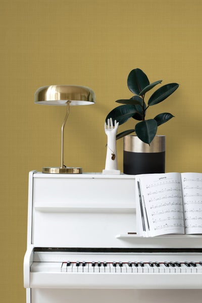 Dekorative Szene mit weißem Klavier, goldener Lampe, Zimmerpflanze und Schmuckhand