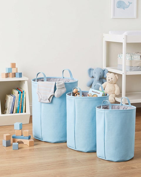 Set aus drei runden Aufbewahrungskörben aus Stoff mit Tragegriffen in einem organisierten Kinderzimmer.