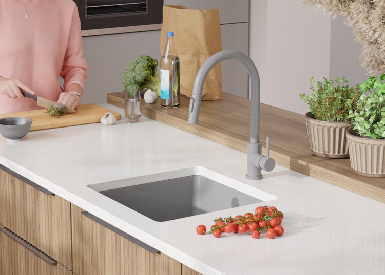 Küchenszene mit Spüle, Armatur, Gemüse und Person beim Kochen