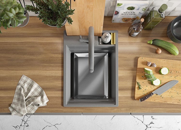 Küchenspüle mit Abtropfschale, Armatur, Spülmittelspender und Küchenutensilien auf einer Arbeitsplatte.