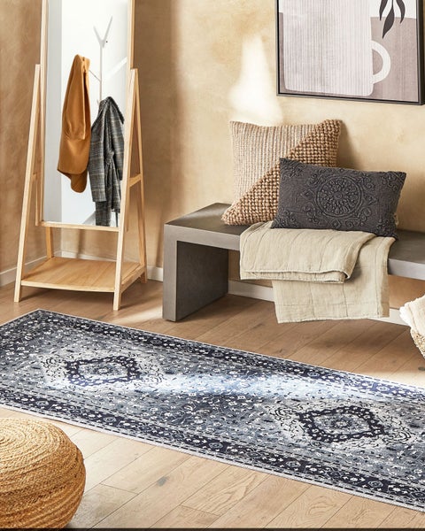 Einrichtungsansicht mit gemustertem Teppich, Bank, Kissen und Kleiderständer