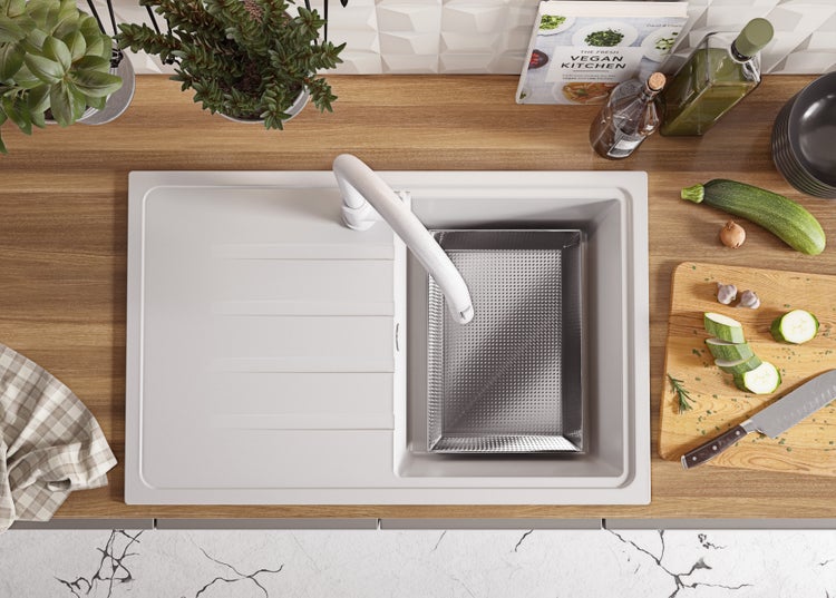 Ansicht von oben auf eine Küche mit Spüle, Wasserhahn, Schneidebrett, Gemüse und Kochbuch