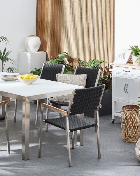 Szene mit Gartentisch mit Glasplatte, Rattanstühlen, Dekoration und Beistellwagen.