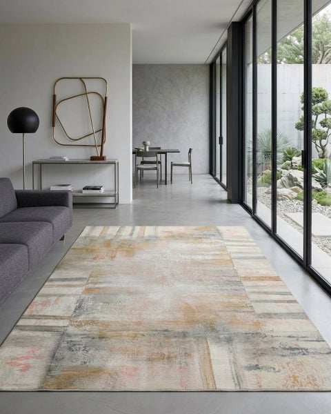 Moderner Wohnbereich mit einem großen abstrakt gemusterten Teppich im Vintage Look auf grauem Boden neben einem Sofa und bodentiefer Fensterfront