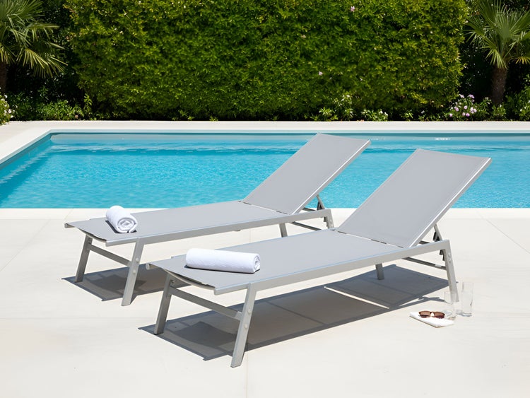 Zwei graue Sonnenliegen aus Aluminium am Pool